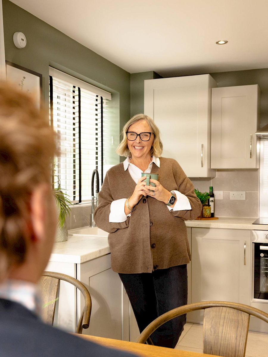 Woman smiling in kitchen with drink in hand