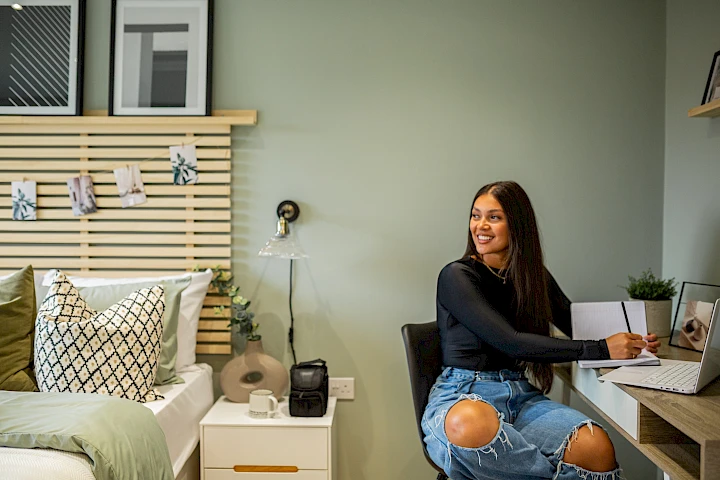 Young woman in a bedroom sat at desk