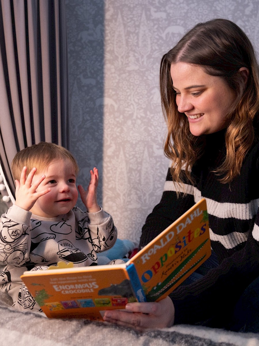 Woman reading book to child in bed