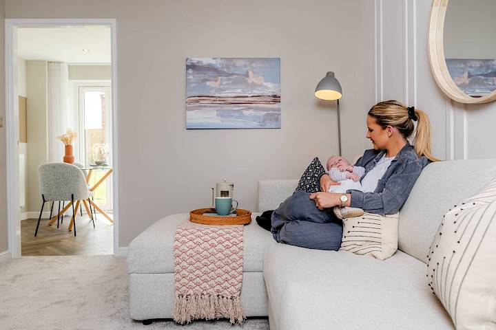 Woman holding baby whilst sat on sofa