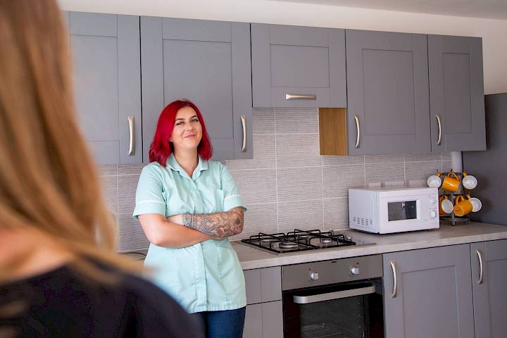 Female nurse stood in kitchen with arms crossed
