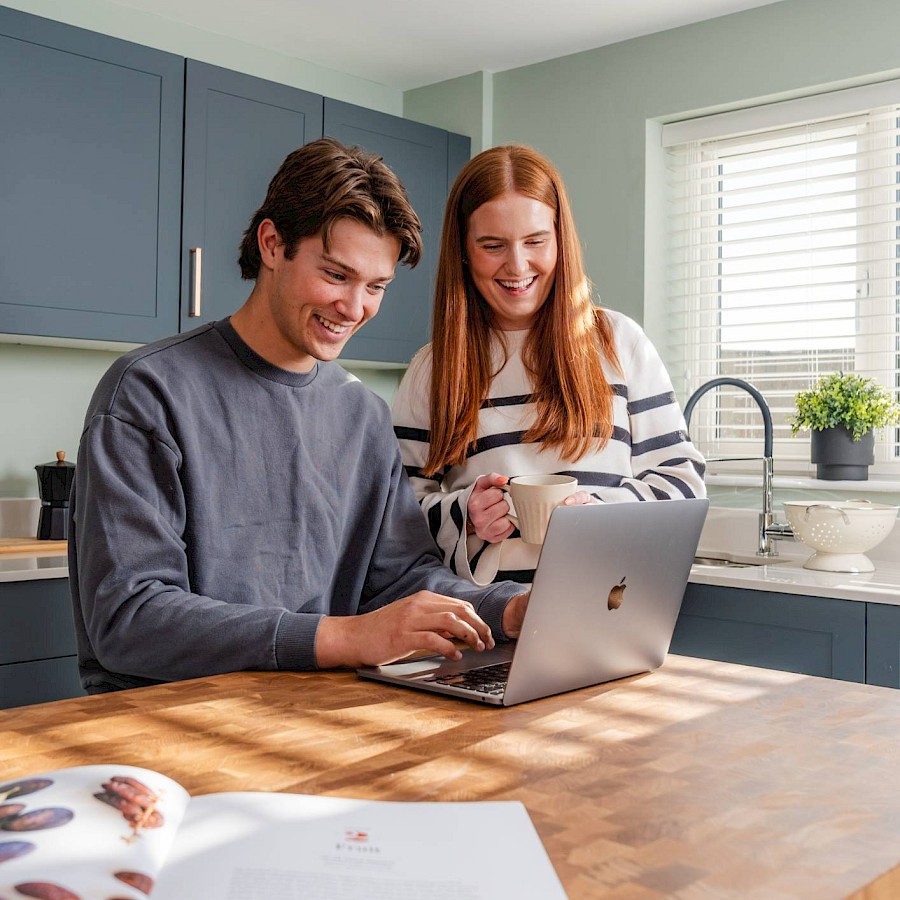 Young couple smiling and looking at laptop
