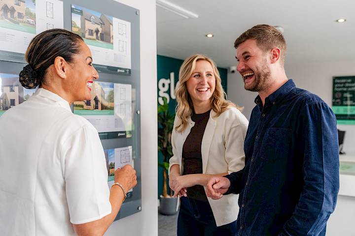 Male and female speaking with a sales advisor in a new homes sales centre